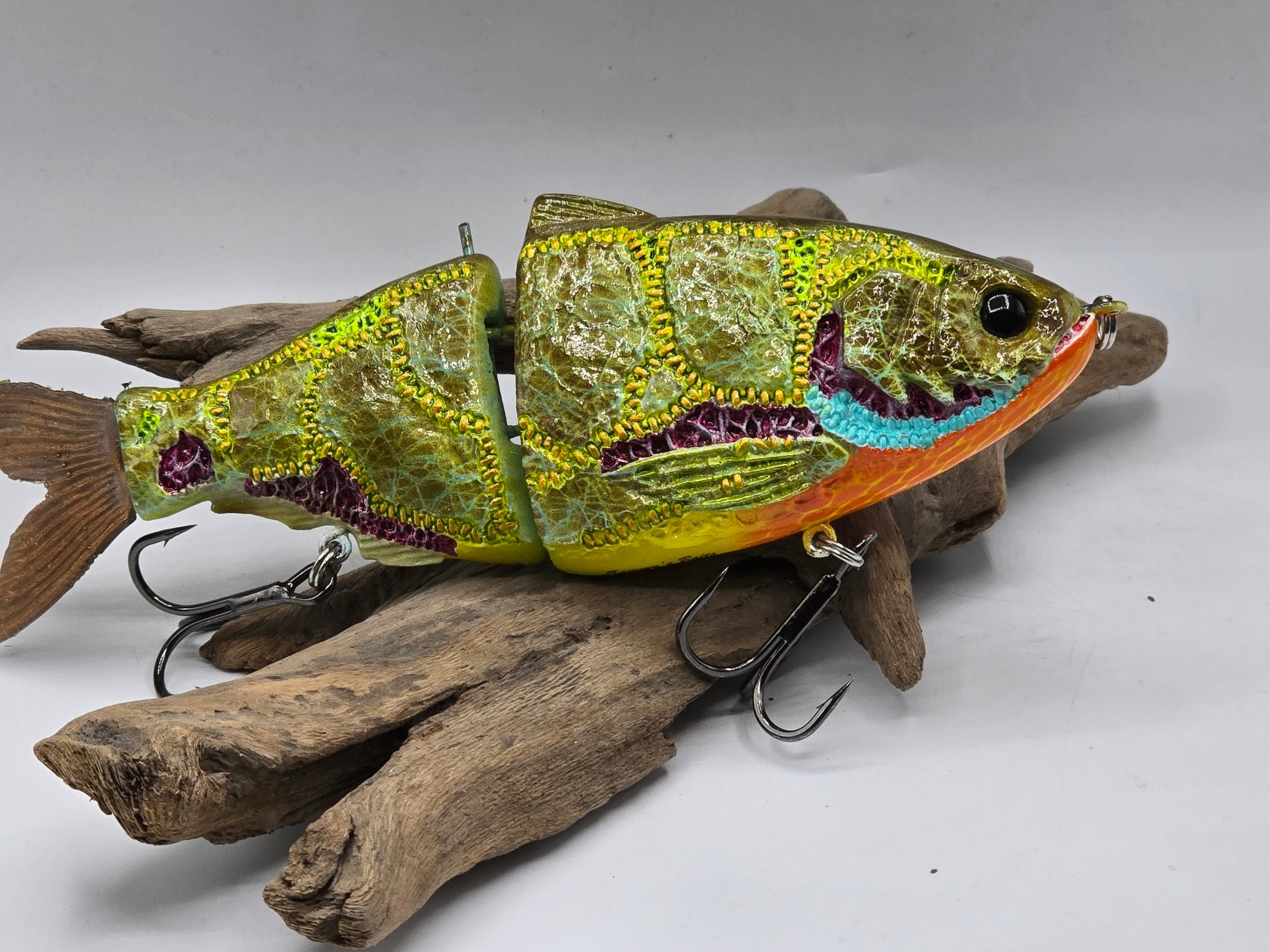 Colorful fishing lure on a piece of driftwood against a gray background